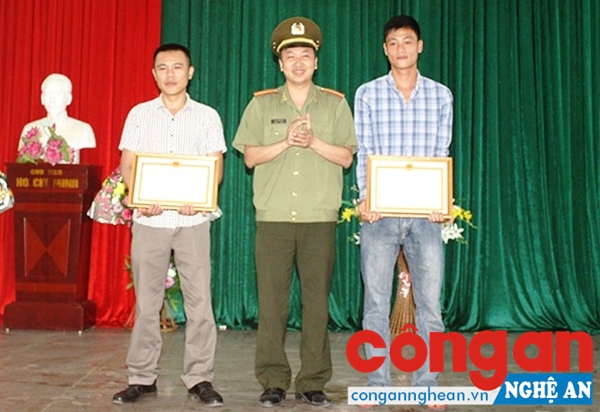 Thừa ủy quyền của Giám đốc Công an tỉnh, Trưởng Phòng xây dựng phong trào toàn dân bảo vệ ANTQ Công an tỉnh Nghệ An trao Giấy khen cho 2 anh Đặng Anh Dũng và Trương Công Vinh - Ảnh: Xuân Thống