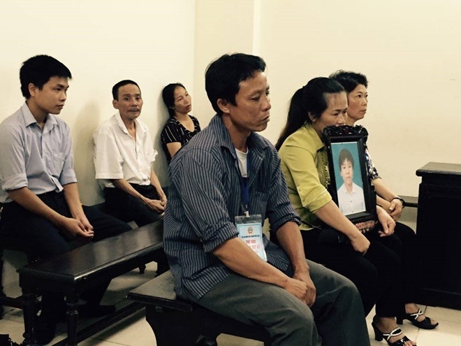 Mẹ nạn nhân ôm di ảnh con, mẹ bị cáo thẫn thờ phía sau.