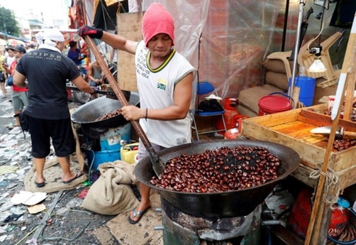 Một thanh niên Philippines nướng hạt dẻ chào mừng Năm mới. Ảnh: Reuters