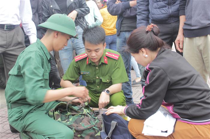 Gia đình và các tân binh kiểm tra đồ dùng trước khi lên xe nhận nhiệm vụ