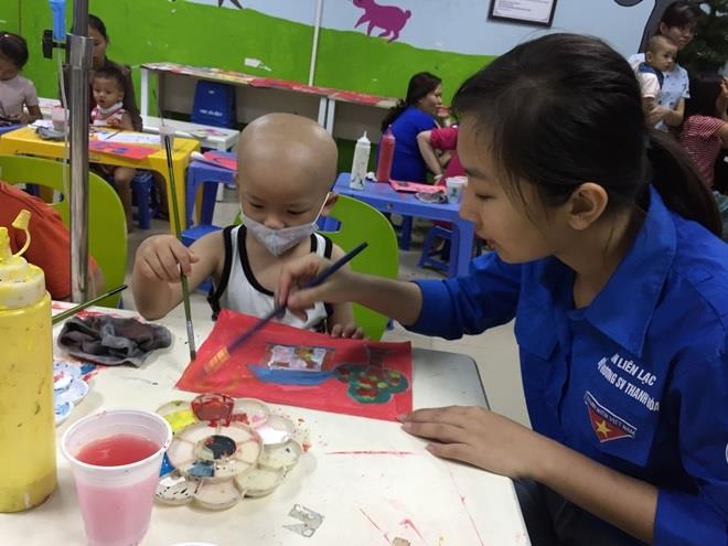  Chị tình nguyện viên hướng dẫn cho bé cách vẽ.