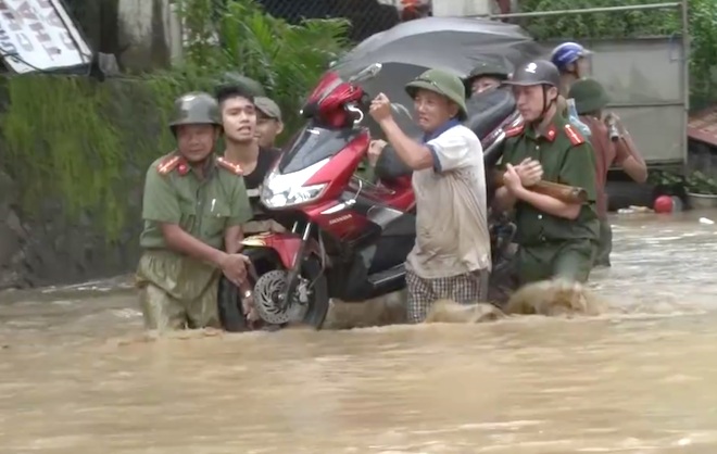 Lực lượng chức năng giúp người dân di dời tài sản ra khỏi vùng lũ. (Ảnh: Duy Khánh).