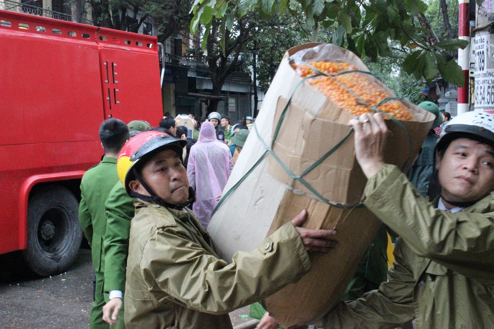2 người đàn ông nỗ lực vác một thùng bánh khỏi khu vực nguy hiểm