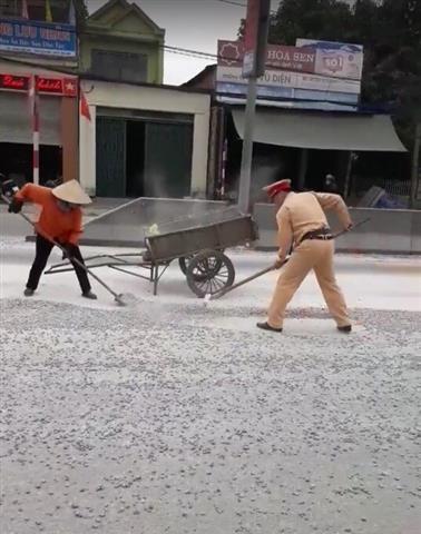 Cảnh sát giao thông dọn đá dăm rơi vãi trên đường