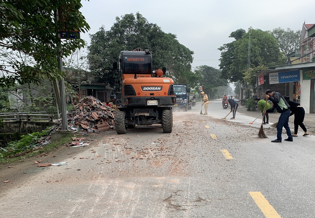 Lực lượng Cảnh sát giao thông cùng người dân thu dọn vật liệu rơi vãi