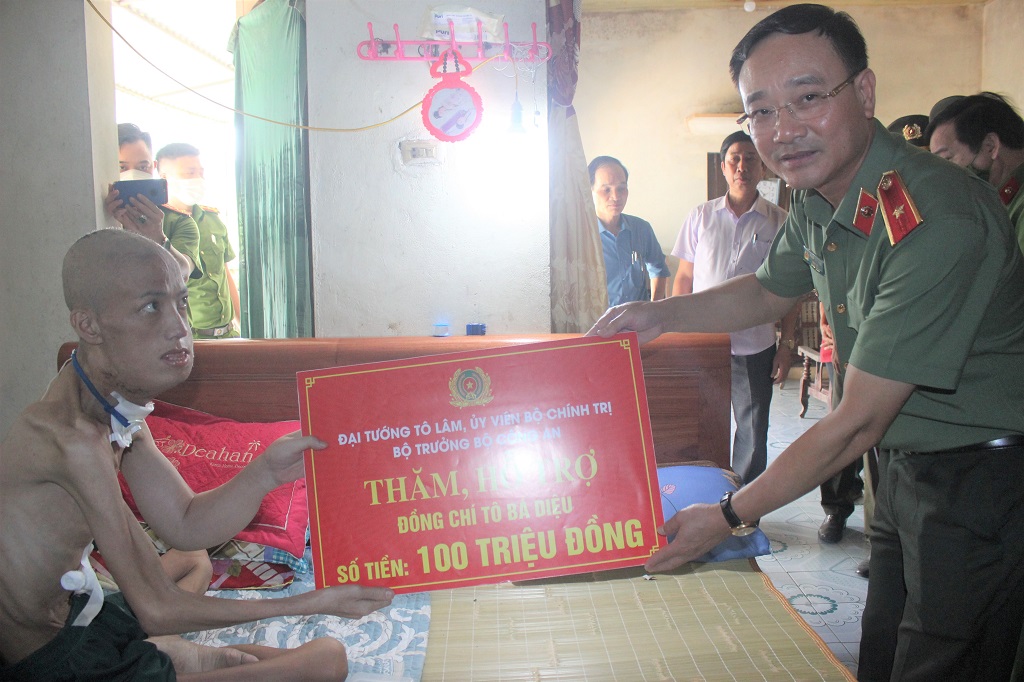 Đồng chí Thiếu tướng Phạm Thế Tùng, Giám đốc Công an tỉnh Nghệ An trao số tiền 100 triệu đồng của đồng chí Đại tướng Tô Lâm, Ủy viên Bộ Chính trị, Bộ trưởng Bộ Công an cho đồng chí Diệu 