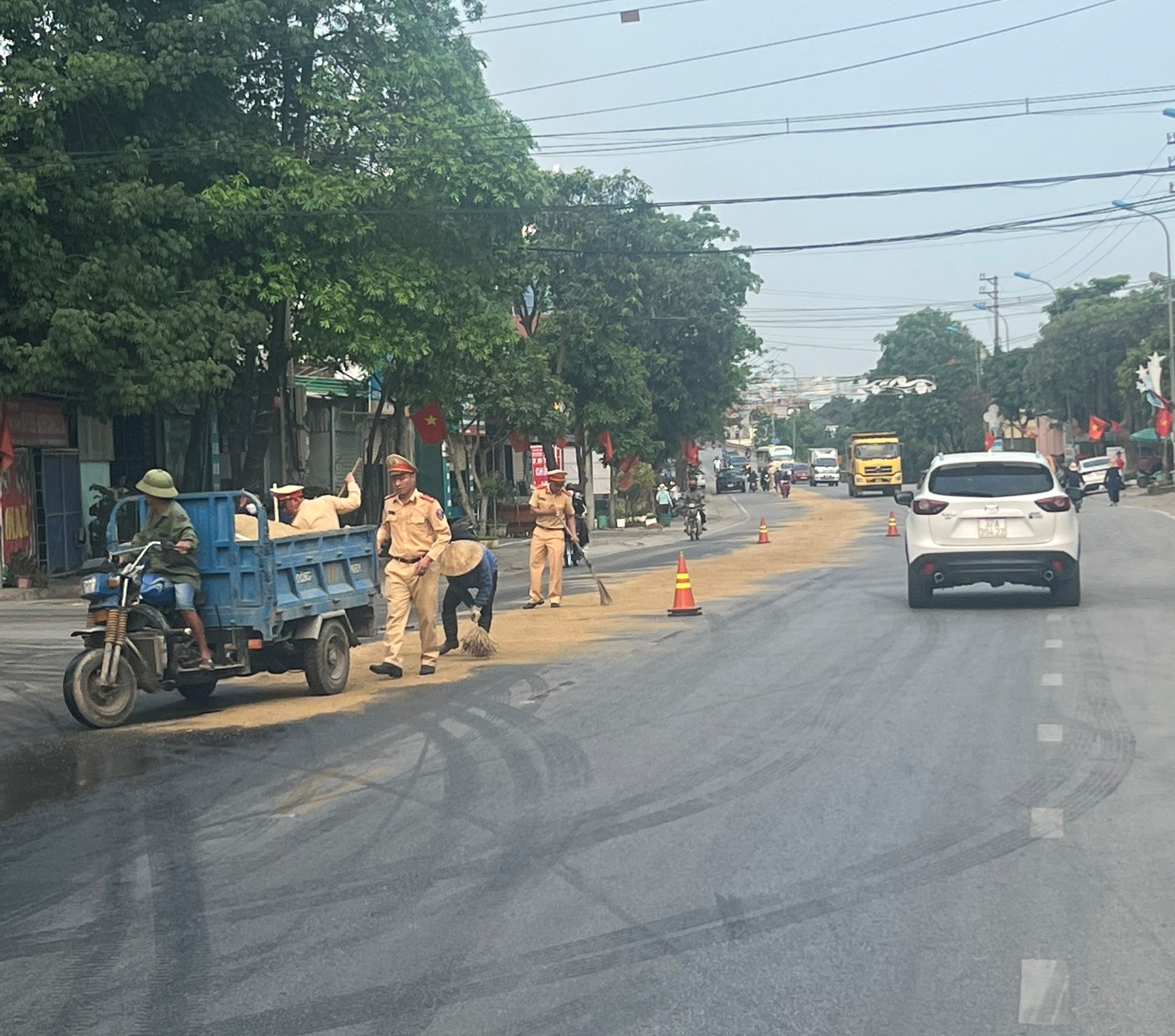 Lực lượng Cảnh sát giao thông Công an thị xã Thái Hòa dùng cát, chổi để xử lý số dầu tràn ra đường, giúp đảm bảo an toàn cho người tham gia giao thông