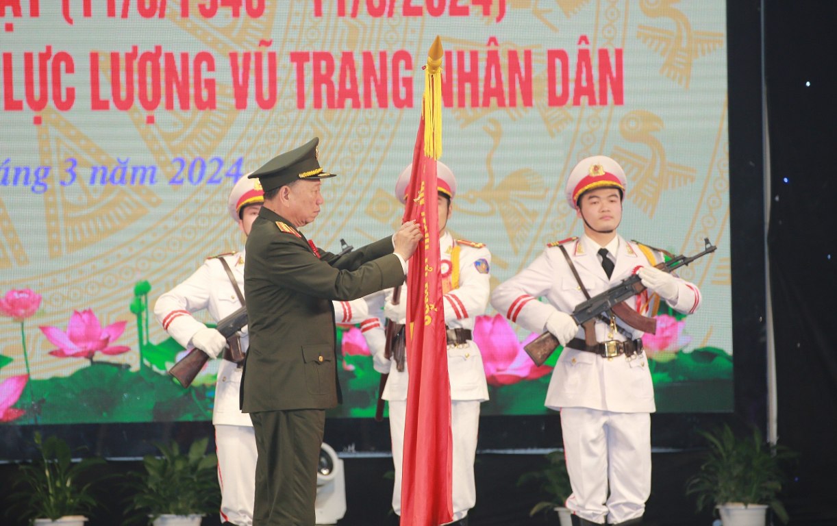 Thừa ủy quyền của Chủ tịch nước, Đại tướng Tô Lâm - Ủy viên Bộ Chính trị, Bí thư Đảng ủy Công an Trung ương, Bộ trưởng Bộ Công an gắn Huy hiệu Anh hùng lực lượng vũ trang nhân dân lên lá cờ truyền thống của Công an tỉnh Nghệ An
