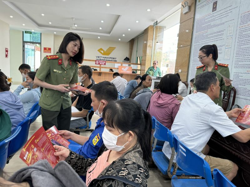 Cán bộ Phòng Quản lý xuất nhập cảnh Công an Nghệ An tuyên truyền, phát tờ rơi về Luật Căn cước tại bộ phận một cửa