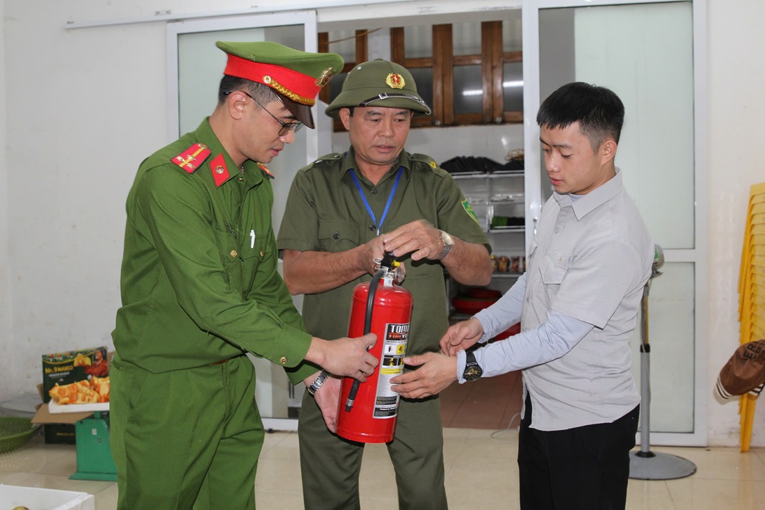Ông Phạm Trọng Tạo (giữa) cùng cán bộ Công an phường Trường Thi hướng dẫn người dân sử dụng bình chữa cháy để phòng, chống cháy nổ