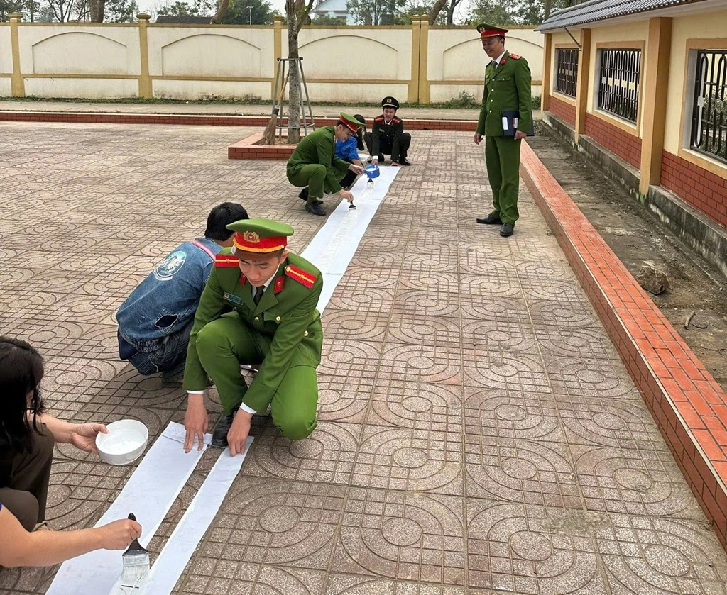 Công an xã phối hợp Đoàn xã sơn kẻ các ô vị trí, vạch dừng đỗ dành riêng cho xe của phụ huynh