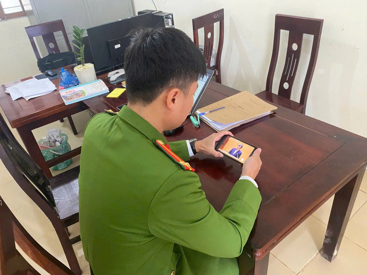 Cán bộ Công an xã Anh Sơn chăm chú theo dõi truyền hình trực tiếp Hội nghị qua điện thoại di động