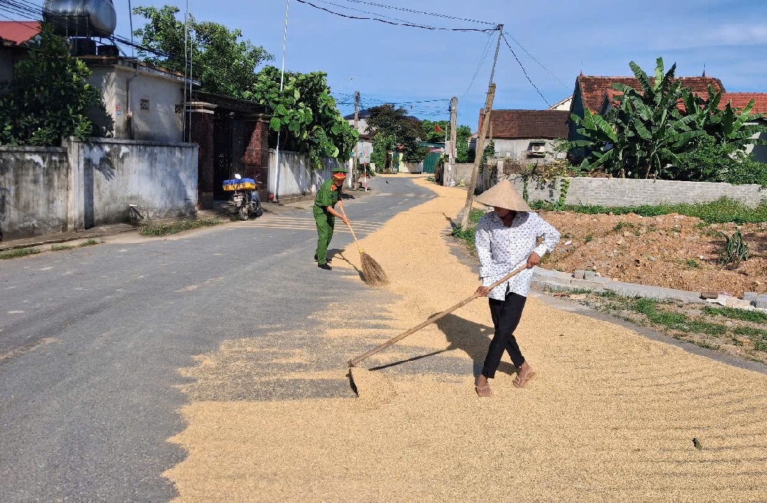 Công an xã Nghĩa Khánh và Nam Đàn giúp người dân thu dọn lúa phơi trên đường