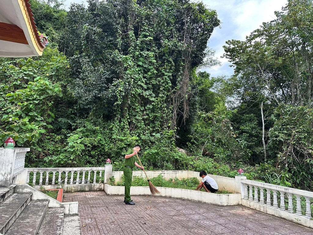 Công an xã và học sinh tham gia quét dọn, nhổ cỏ khuôn viên Nhà bia tưởng niệm các Anh hùng liệt sĩ